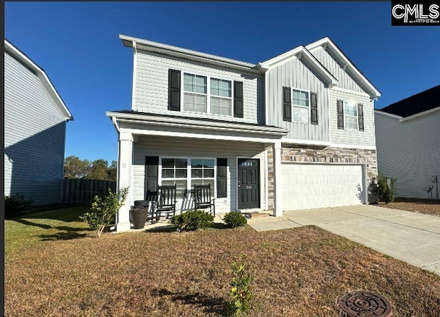 view of front of house featuring covered porch, a garage, and a front lawn