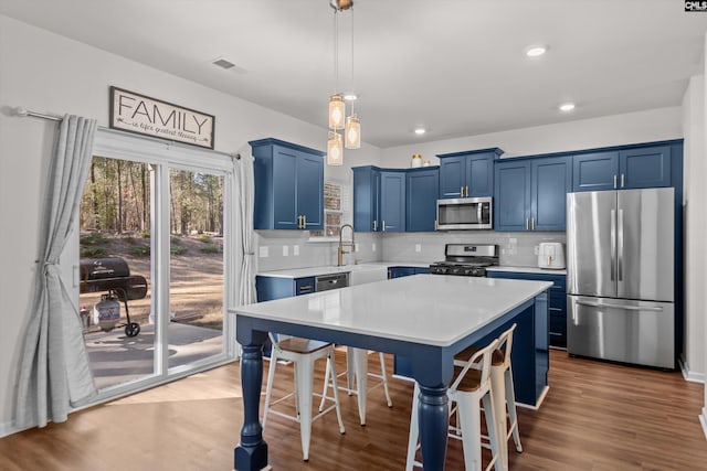 kitchen with a breakfast bar, appliances with stainless steel finishes, blue cabinets, and a kitchen island