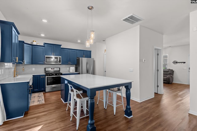 kitchen featuring tasteful backsplash, a center island, appliances with stainless steel finishes, a kitchen breakfast bar, and blue cabinetry