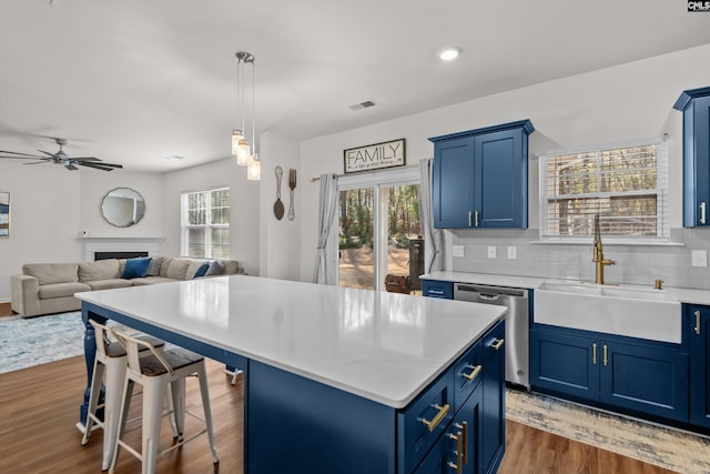 kitchen with dark hardwood / wood-style flooring, dishwasher, blue cabinets, and a center island