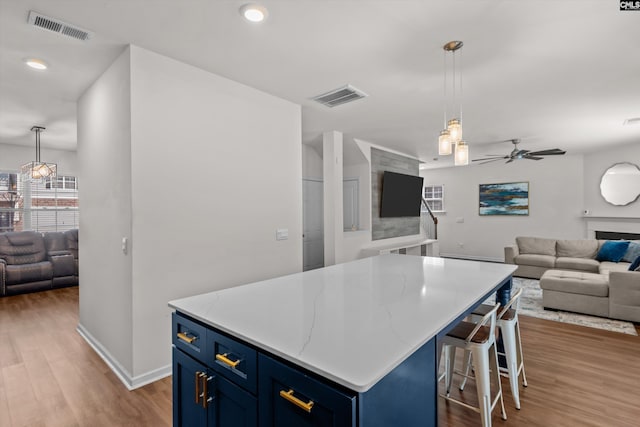 kitchen featuring a center island, dark hardwood / wood-style flooring, hanging light fixtures, ceiling fan, and blue cabinets