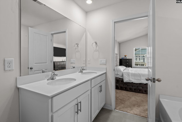 bathroom featuring lofted ceiling, vanity, and a bathing tub