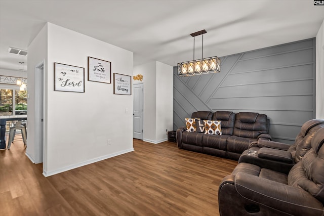 living room with wood-type flooring, a notable chandelier, and wooden walls