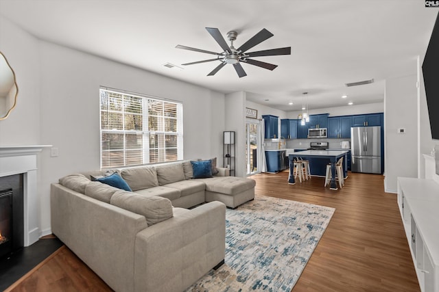 living room featuring ceiling fan and dark wood-type flooring