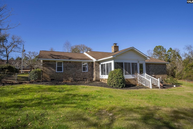 back of property featuring a sunroom and a lawn