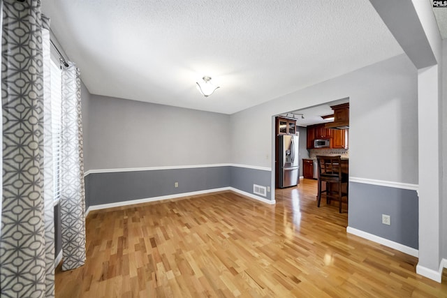 unfurnished living room featuring light wood-type flooring and a textured ceiling