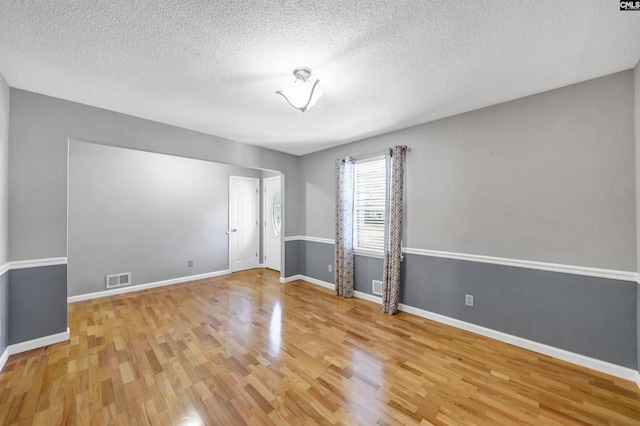 unfurnished room featuring a textured ceiling and light hardwood / wood-style flooring