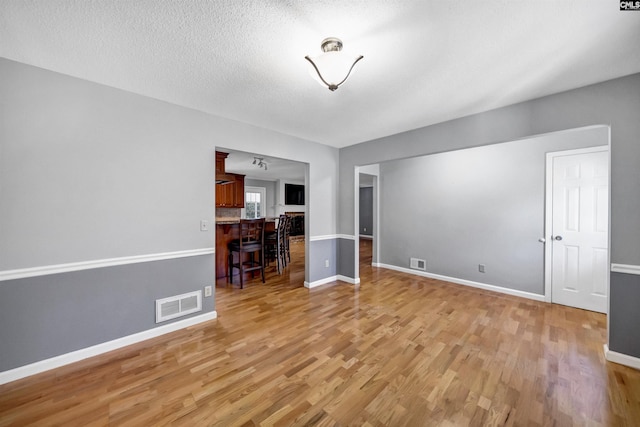 unfurnished living room featuring a textured ceiling and light hardwood / wood-style flooring