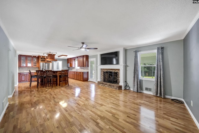 unfurnished living room featuring ceiling fan, light hardwood / wood-style floors, a fireplace, and plenty of natural light