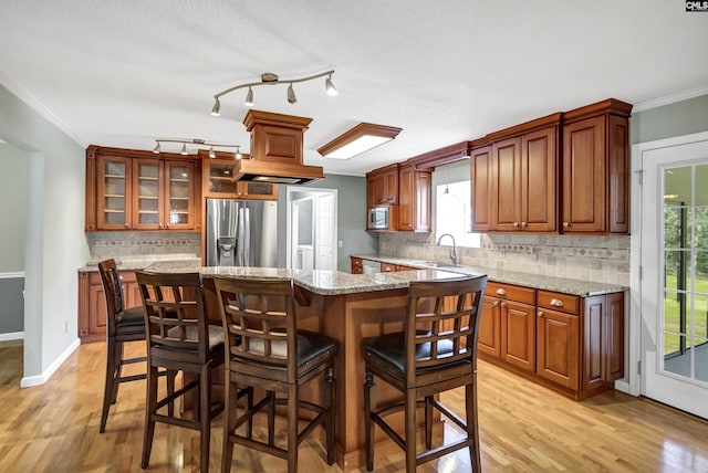 kitchen with light hardwood / wood-style floors, a kitchen island, crown molding, stainless steel appliances, and light stone counters