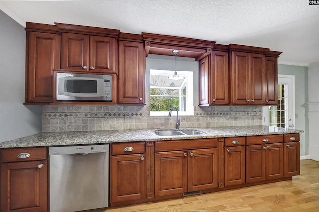 kitchen with appliances with stainless steel finishes, light hardwood / wood-style floors, sink, hanging light fixtures, and crown molding