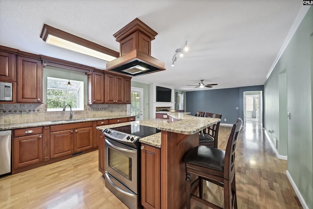 kitchen with sink, appliances with stainless steel finishes, a kitchen breakfast bar, ornamental molding, and light stone counters