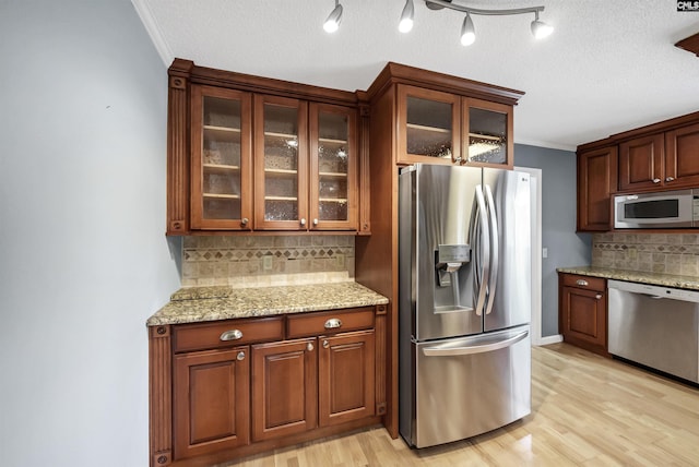 kitchen with light wood-type flooring, decorative backsplash, stainless steel appliances, and ornamental molding