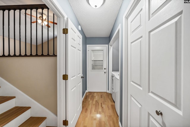 hallway featuring a textured ceiling, washer and dryer, and light hardwood / wood-style floors