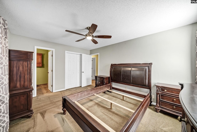 bedroom featuring ceiling fan, a textured ceiling, a closet, and light carpet