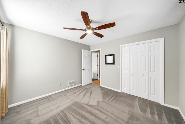 unfurnished bedroom featuring a textured ceiling, ceiling fan, a closet, and carpet floors