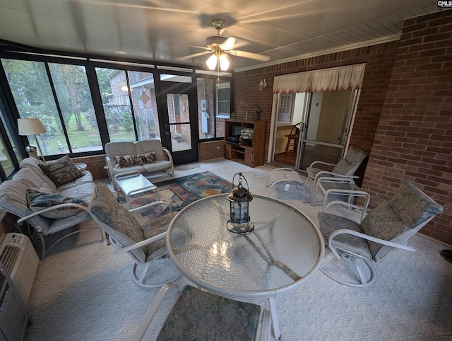 carpeted living room featuring brick wall and ceiling fan