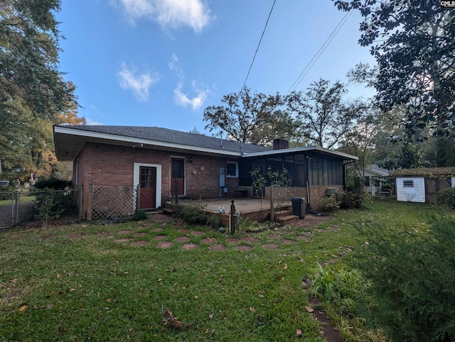 rear view of property featuring a sunroom, a yard, a shed, and a patio