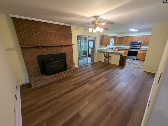 kitchen featuring kitchen peninsula, sink, dark wood-type flooring, a breakfast bar, and stainless steel appliances