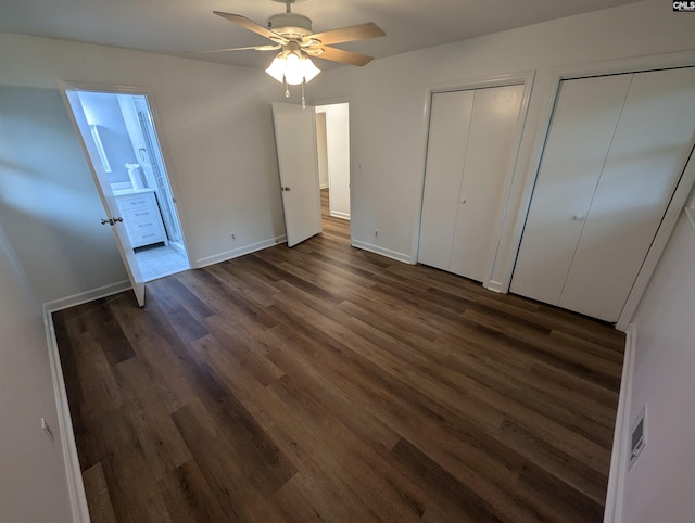 unfurnished bedroom with ceiling fan, dark hardwood / wood-style flooring, ensuite bath, and multiple closets