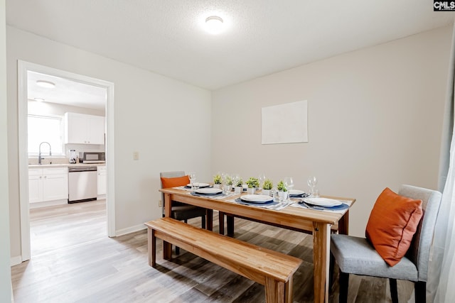 dining area with sink, a textured ceiling, and light hardwood / wood-style flooring