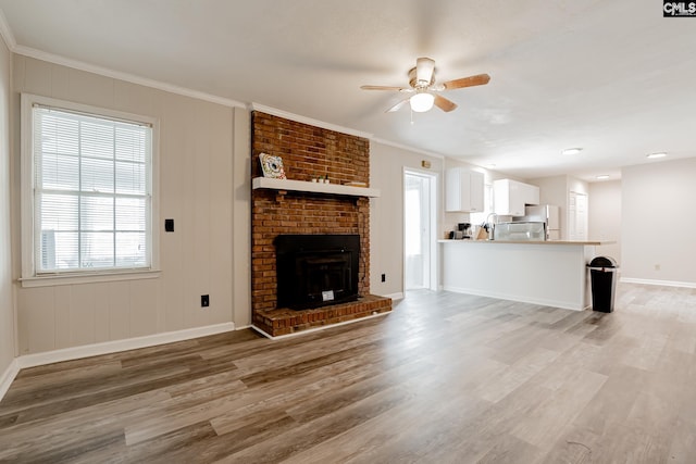 unfurnished living room with hardwood / wood-style flooring, a brick fireplace, ornamental molding, and ceiling fan