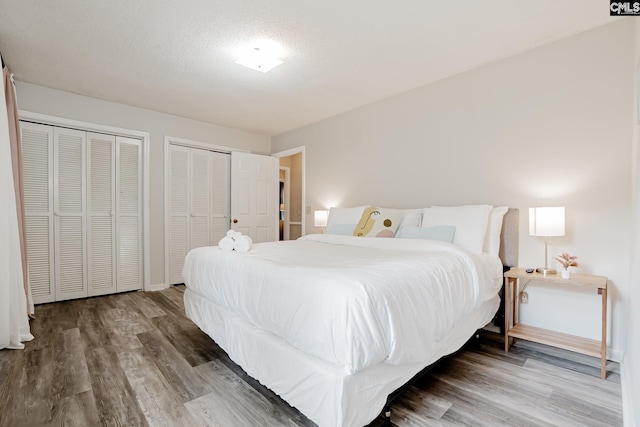 bedroom featuring hardwood / wood-style flooring, two closets, and a textured ceiling