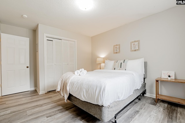 bedroom featuring light hardwood / wood-style floors, a textured ceiling, and a closet