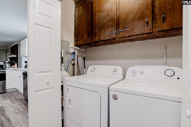 clothes washing area with cabinets, light wood-type flooring, and washer and dryer