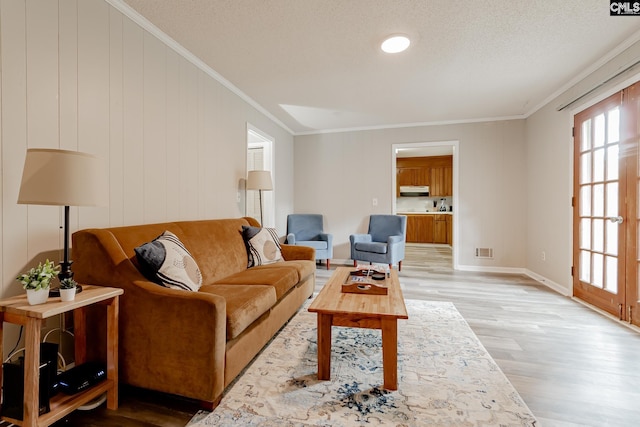 living room with light hardwood / wood-style flooring, crown molding, and a textured ceiling