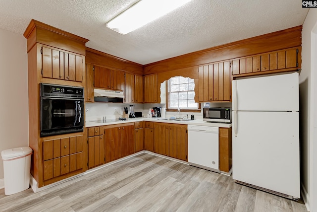 kitchen featuring sink, a textured ceiling, black appliances, and light hardwood / wood-style flooring