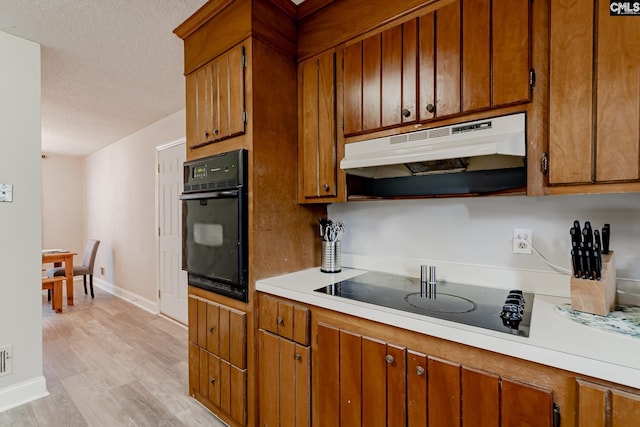 kitchen featuring black appliances, light hardwood / wood-style flooring, and a textured ceiling