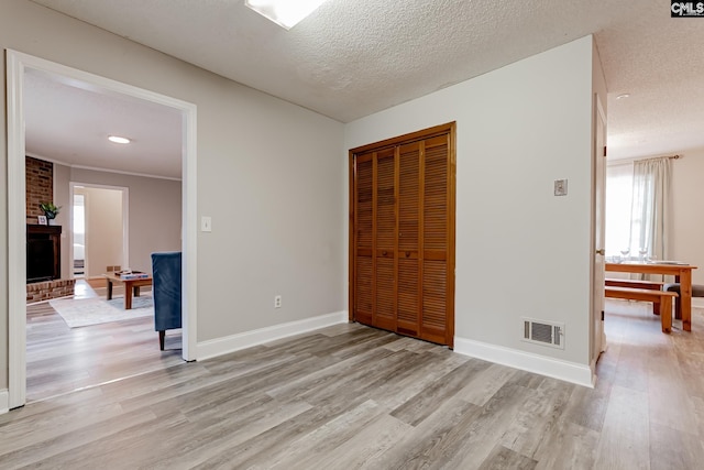 unfurnished bedroom with light hardwood / wood-style floors, a textured ceiling, and a closet