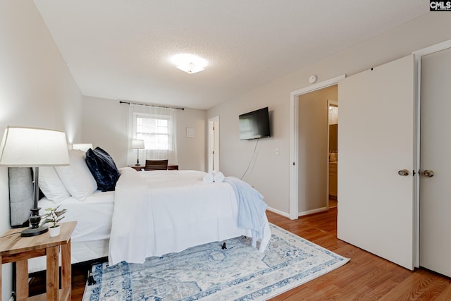 bedroom with a textured ceiling and light hardwood / wood-style flooring