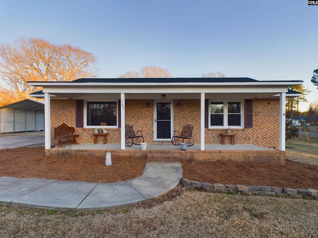 single story home featuring a porch and a carport