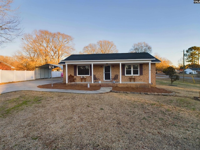 view of front of house featuring covered porch, a carport, and a front lawn