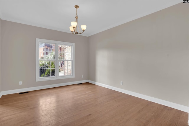 spare room with light hardwood / wood-style floors and an inviting chandelier