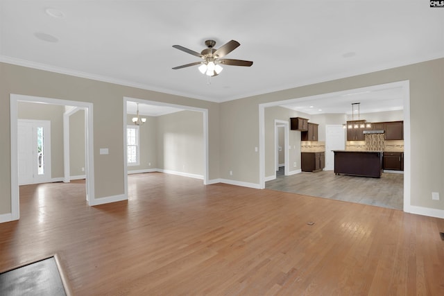 unfurnished living room featuring ceiling fan with notable chandelier and light hardwood / wood-style flooring