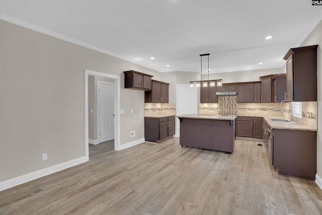 kitchen featuring pendant lighting, light hardwood / wood-style flooring, sink, backsplash, and a kitchen island