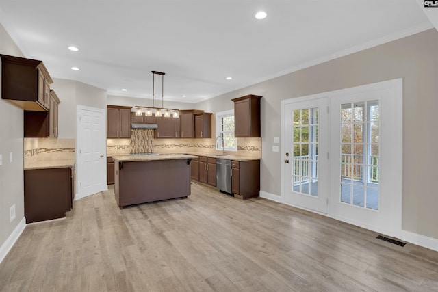 kitchen with stainless steel dishwasher, decorative light fixtures, backsplash, a kitchen island, and light hardwood / wood-style floors