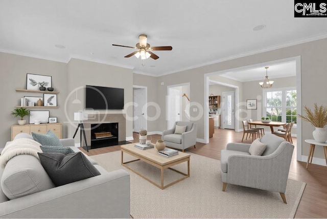 living room with light hardwood / wood-style floors, ceiling fan with notable chandelier, and ornamental molding