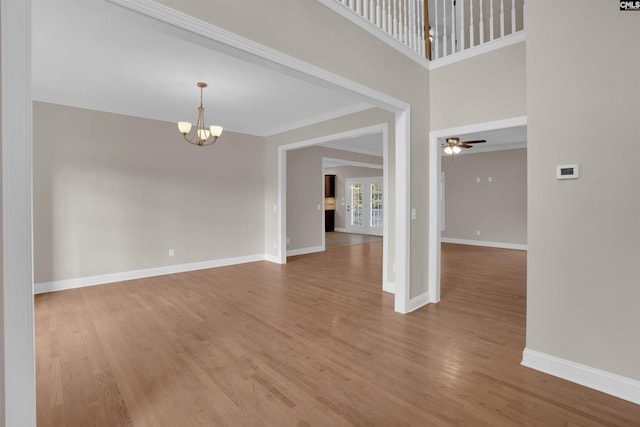 spare room featuring ceiling fan with notable chandelier and hardwood / wood-style flooring