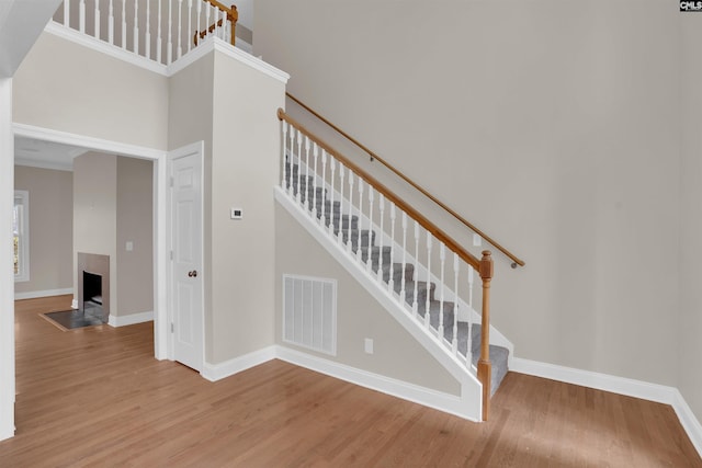 staircase with a high ceiling, crown molding, and wood-type flooring