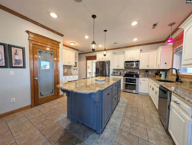 kitchen with pendant lighting, appliances with stainless steel finishes, a center island, sink, and backsplash