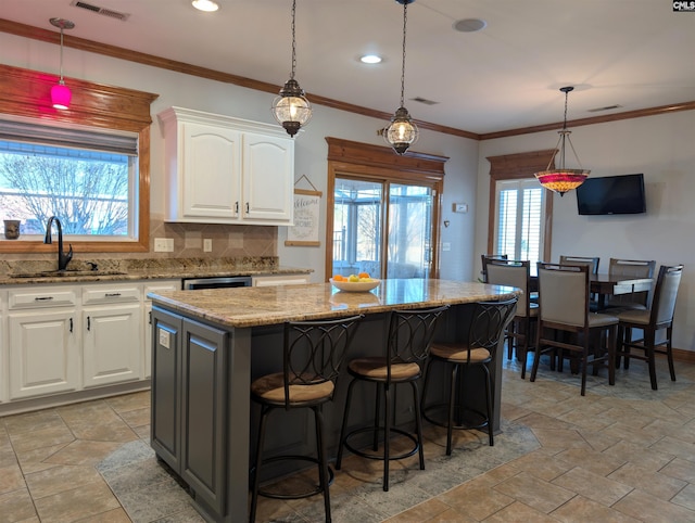 kitchen with pendant lighting, backsplash, a center island, and white cabinetry