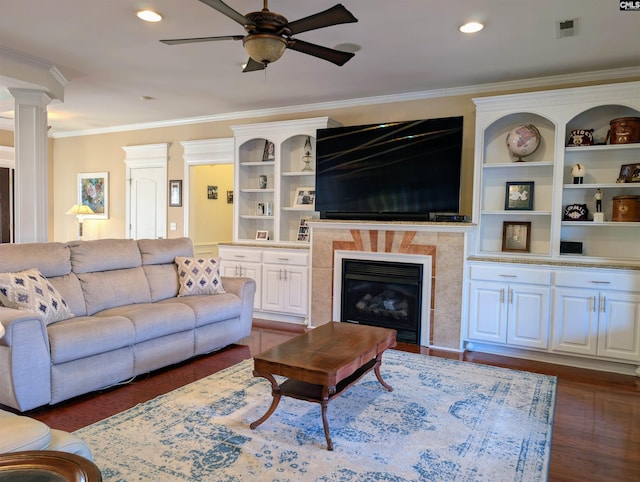 living room with ceiling fan, a fireplace, dark hardwood / wood-style floors, ornamental molding, and decorative columns