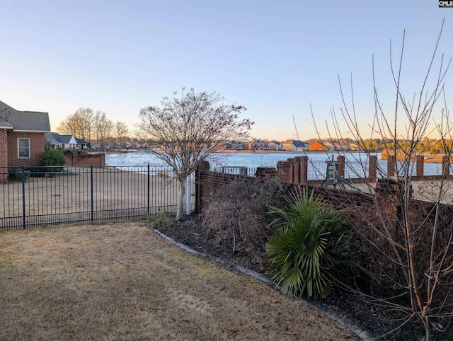 yard at dusk featuring a water view