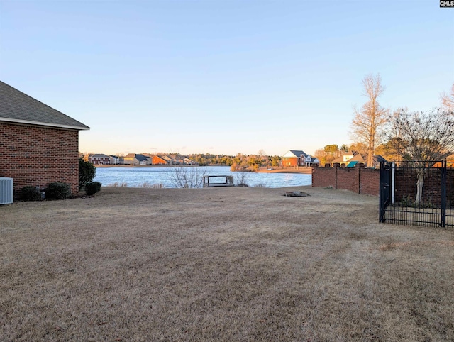 yard at dusk with central air condition unit and a water view