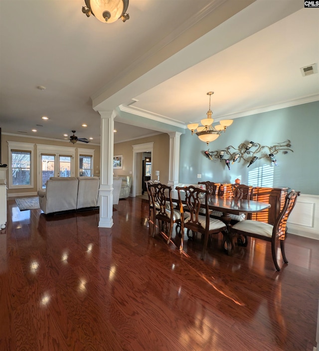 dining space with decorative columns, ceiling fan with notable chandelier, crown molding, and dark hardwood / wood-style floors