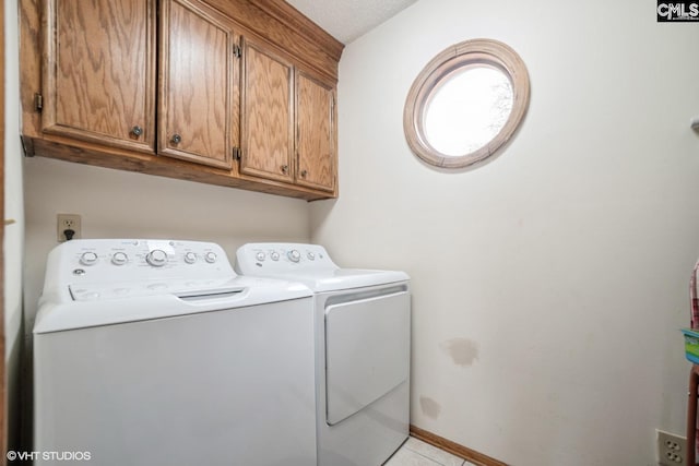 washroom featuring cabinets, a textured ceiling, and washer and clothes dryer